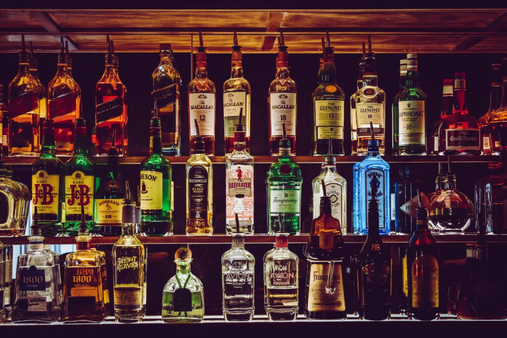 An array of various liquor bottles beautifully displayed on a bar shelf.