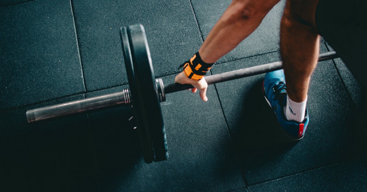 Close-up of a person lifting a barbell in an indoor gym, focusing on strength training.