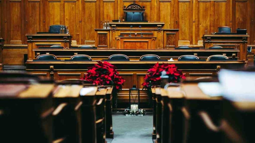 Empty wooden parliament hall with seats and flowers, representing leadership, strategy, and the legacy of the Father of Modern Political Science.